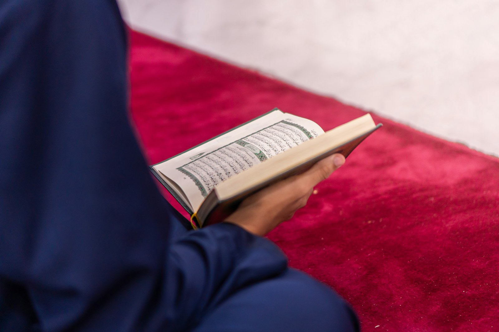 A learner holding and studying a copy of the Qur’an